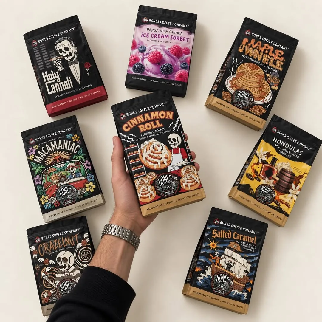 A hand holding Cinnamon Roll among other Bones Coffee bags